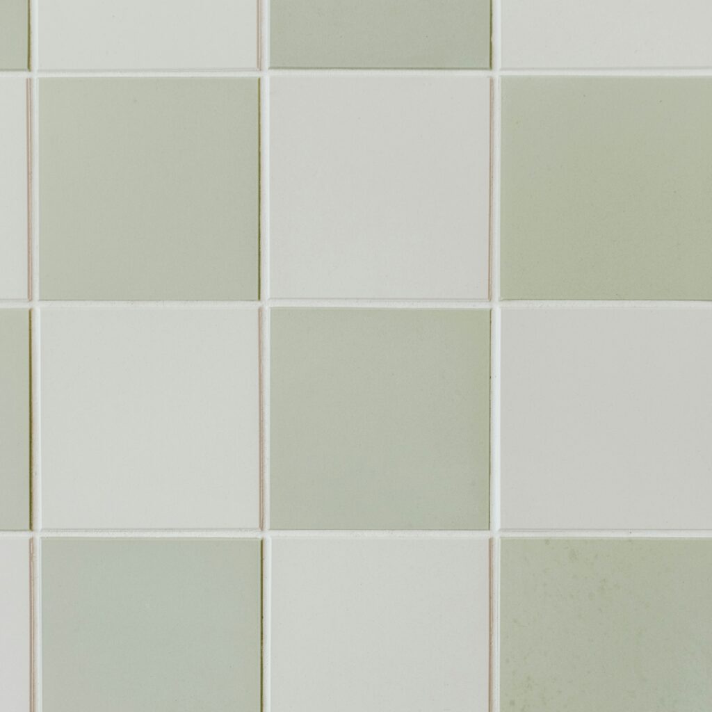 A pattern of square tiles in varying shades of green and white, arranged in a grid formation.